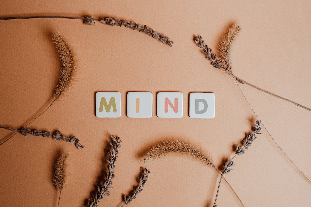 Home Flat lay of the word 'MIND' surrounded by dried flowers on a warm backdrop.