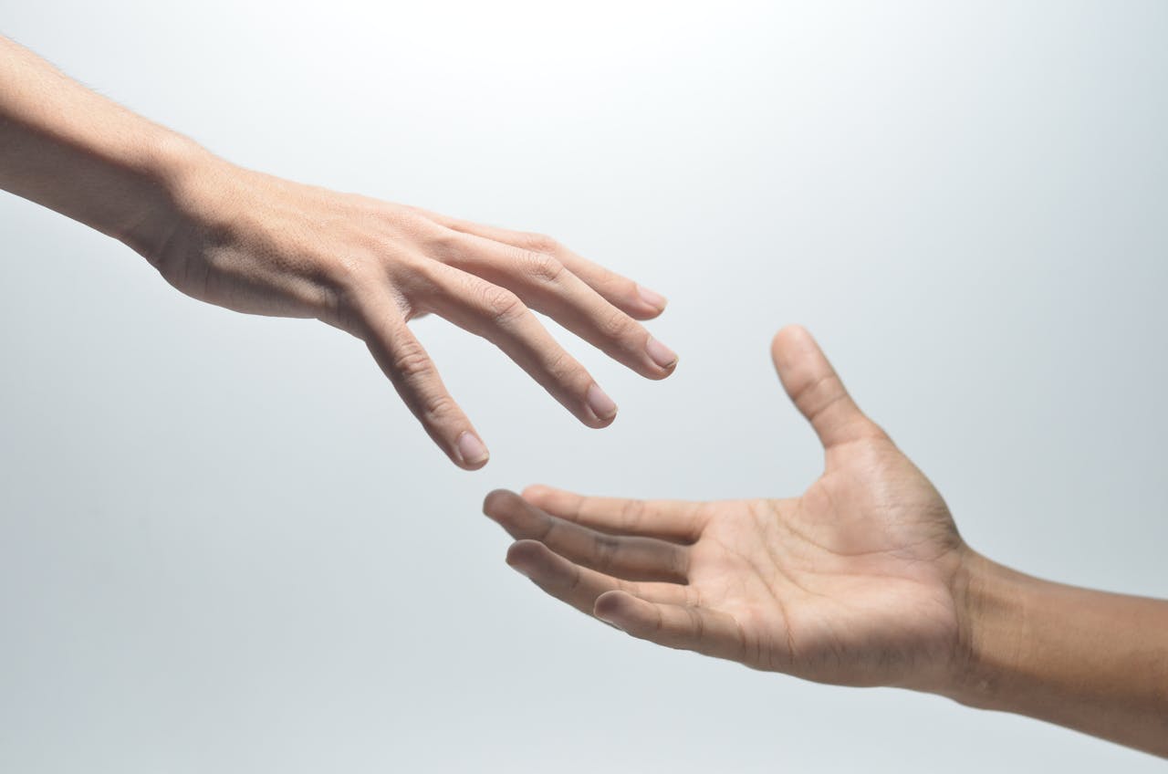Home Close-up of two hands reaching towards each other on a neutral background, symbolizing connection.